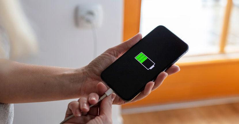 Hands plugging in and charging smart phone